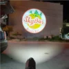 Logo SkyBar Beach Bar được chiếu lên tường ngoài của một toà nhà vào ban đêm, đèn chiếu đặt dưới đất phía trước